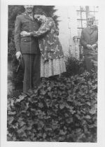 Mother hugging soldier standing on steps outside house, unknown