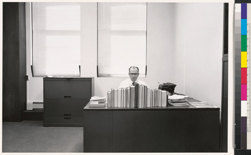 [Office worker seated at a desk behind books, Standard Oil Company of California.]