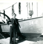 Photograph of Cooper Atop the USS Dixie Next To An Ad 14 Boat