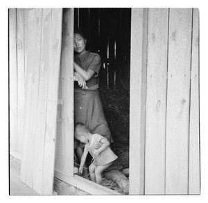 Boy in doorway of house, with mother inside, Korea