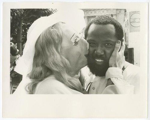 Person in pig mask kissing smiling man