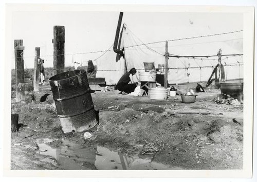 A woman amidst migrant workers housing, circa 1930