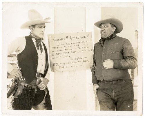 Ranchers in front of sign