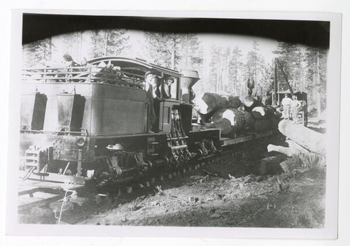 Men standing in the engine of a lumber train