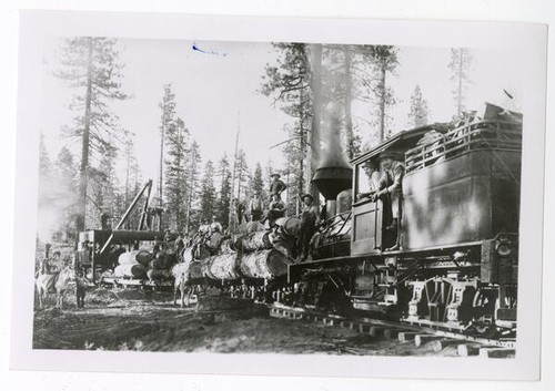 Workers atop a loaded lumber train