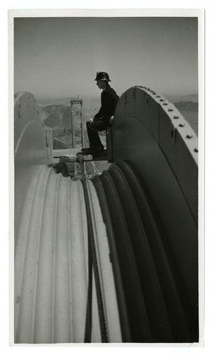 Golden Gate Bridge construction worker resting atop cable pulley