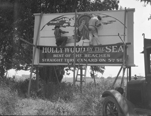 Men Painting Hollywood by the Sea Sign