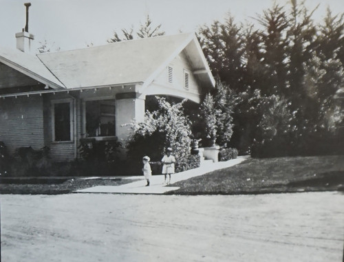 Two Children Standing in Front of House