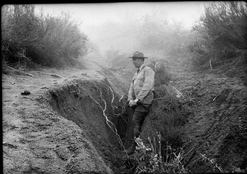 Floods and Storm Damage, Walter Powell showing depth of erosion on old Salt Creek Ridge Trail, above Truck Trail. About 3700', NPS Individuals