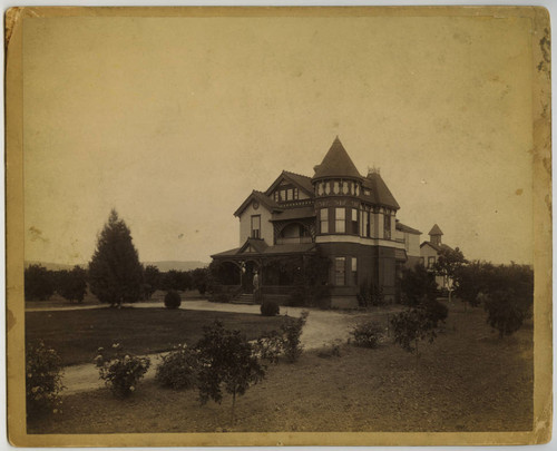 Victorian house and barn with man standing on front porch