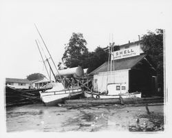 Boats washed ashore by the Shell Marine Products shop by a winter storm, Bodega Bay, California, January 1959