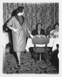 Model in evening dress and coat and Topaz Room customers in the "Dramatic Moods" fashion show in the Topaz Room, Santa Rosa, California, 1959