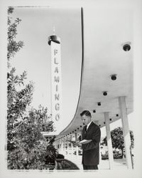 Man with notebook under portico of Flamingo Hotel, Santa Rosa, California, 1964