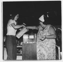 Bank of Marin representative offering a prize to a raffle ticket winner in the Bank of Marin booth at the Sonoma-Marin Fair, Petaluma, California, 1978