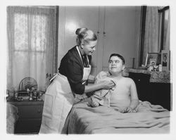 Visiting nurse at administers to a boy in his bed at home, Santa Rosa, California, 1960