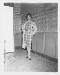 Model in plaid evening dress and a long coat in the "Dramatic Moods" fashion show in the Topaz Room, Santa Rosa, California, 1959