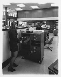 Exchange Bank staff member works at a mobile bill cabinet at the Coddingtown office of the Exchange Bank, Santa Rosa, California, 1972