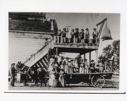 Hop pickers standing on a platform and a wagon