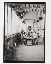 Girls darning socks in the garden room