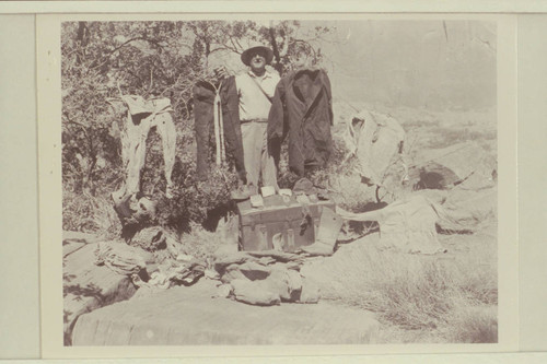 The trunk and contents of B. Graves' trunk found at the Music Temple in Glen Canyon by Harris and others. Photo by Ed Hudson who is holding the clothes and looking at the camera
