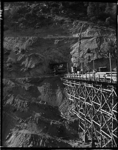 Big Creek 4 construction work: closer shot of bridge structure and mouth of power tunnel. Tunnel mucker is dumping a load of tailings into dump truck at mouth of tunnel