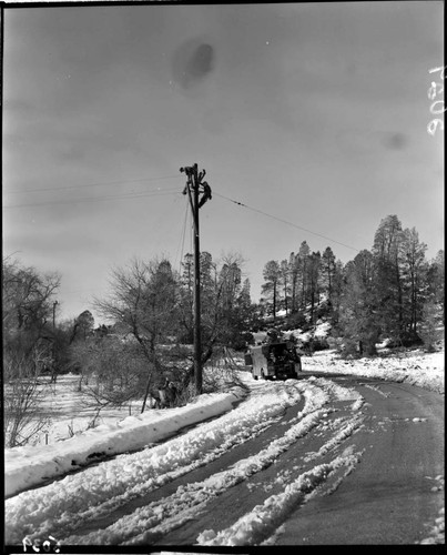 Linemen working at top of pole in the snow