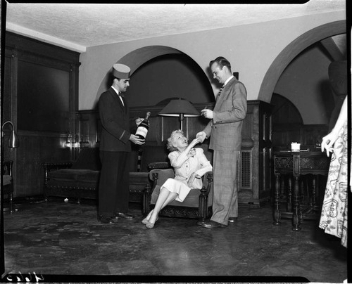 Man with cigar greeting seated woman