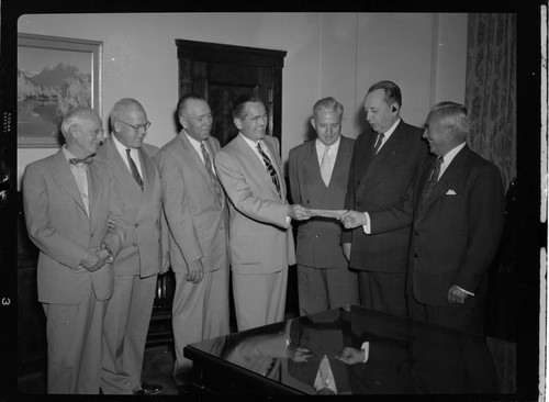 Seven executives posing for check presentation