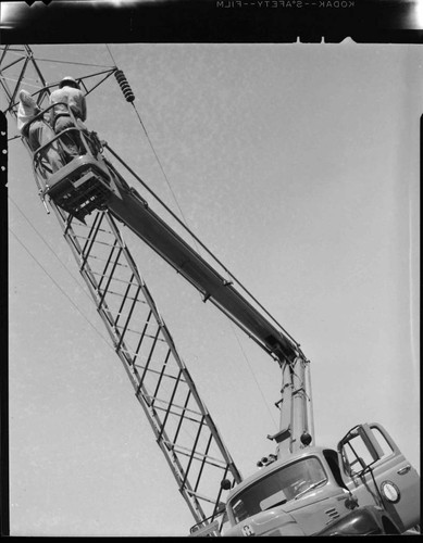 Raising boom to wash insulators on transmission tower