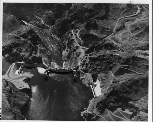 This aerial view shows Hoover Dam, the intake towers, the spillways, and, in the upper right, the electrical substation