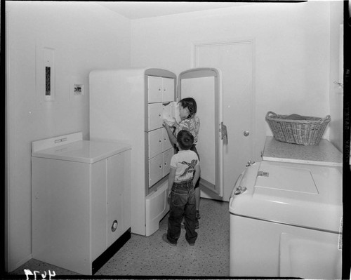 Children taking food out of upright freezer with 8 closed compartments inside