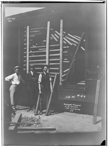 Men standing by a railcar with a damaged shipment of J-M conduit