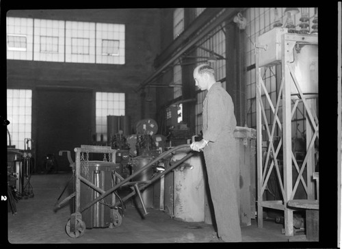 Man moving material with dolly in shop