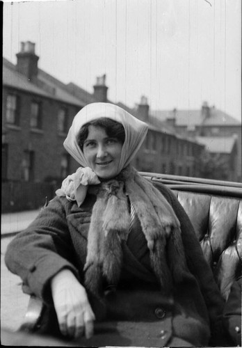 A young woman sitting in a carriage wearing a coat