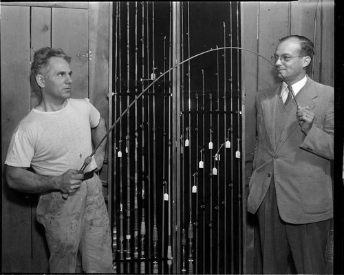 Man testing fishing pole on display