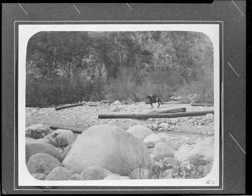 A man on horseback surveying the Santa Ana River 33 KV line washed out by a flood in the canyon