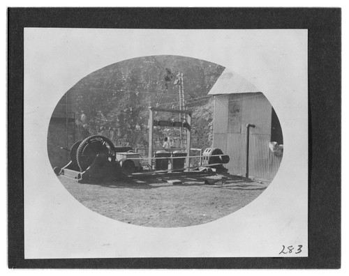 A man standing by the temporary air compressor for the tunnel construction at Kern River #1 Hydro Plant