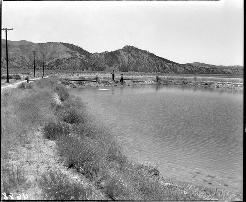 Man and woman standing by a pond in a large open valley