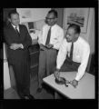 Three men going over blueprints and an Organization Chart for the Montebello Commercial Districts