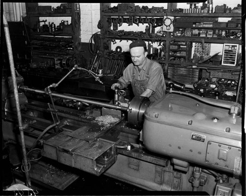 Machinist cutting threads on a long bar with a metal lathe