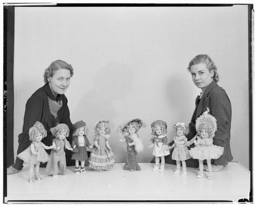 Two women posed with eight of the dolls