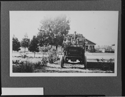 A man sitting in the front seat of an ALCO truck on a suburban street