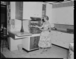 Woman in dress and heels cooking and using electric home appliances