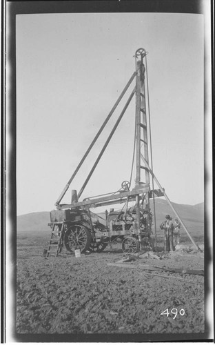 A working crew standing next to well drilling outfit in Tulare County