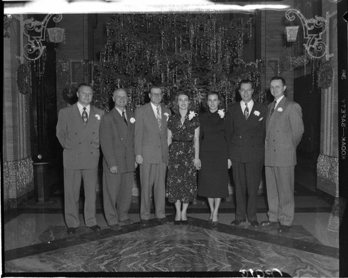 Five men and two women in front of the Christmas tree in the Edison General Office lobby