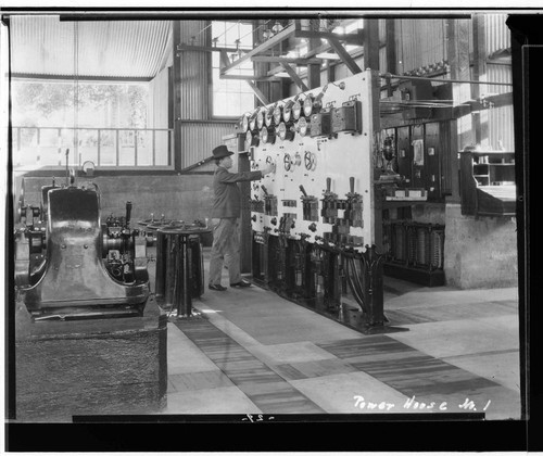 An interior view of Kaweah #1 Power House showing Operator Henry Heard operating the switchboard