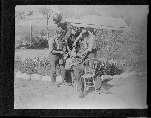 Three men pretending to shave another man with a machete at Mill Creek #1 Hydro Plant