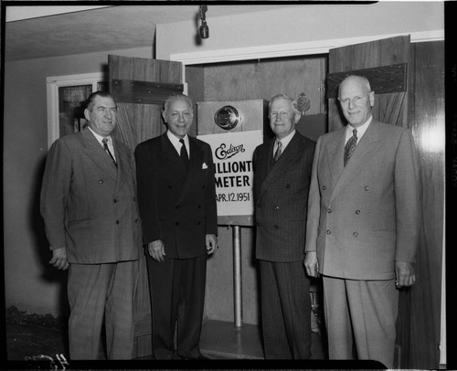 Harold Quinton (second from left) and three other men standing by sign below installed "one millionth" meter in back yard of home