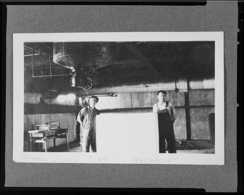 Two men standing in front of soap making equipment at Kerosope Plant