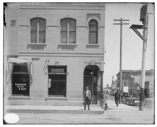 A man standing between the Rossmore Hotel & Cafe and the Santa Ana Local Office